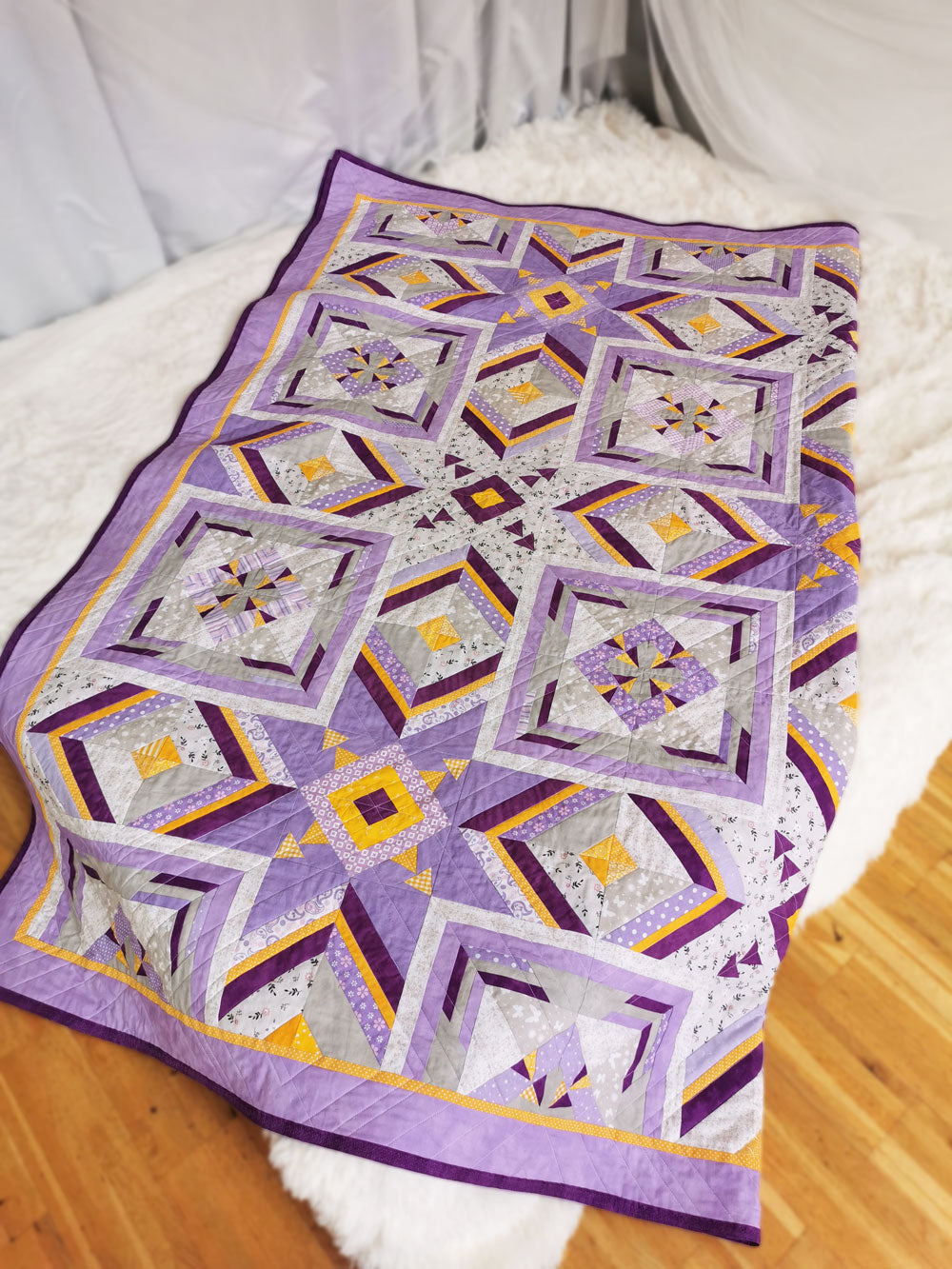 Diagonal display of 'More than Words' quilt, folded to reveal vibrant colors and geometric patterns.