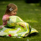 A baby girl unfolding and admiring the Ladybug Wonderland quilt, showcasing its playful design and the soft, inviting texture of the fabric.