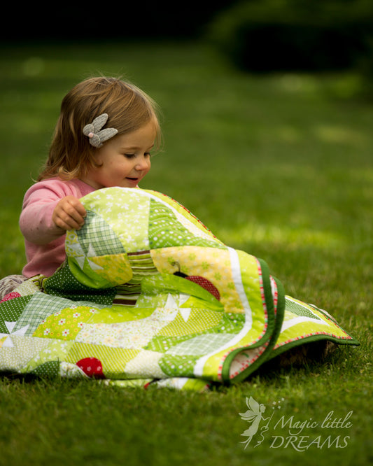 A baby girl unfolding and admiring the Ladybug Wonderland quilt, showcasing its playful design and the soft, inviting texture of the fabric.