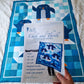 Hand holding the printed Chill and Thrill penguin quilt pattern PDF in front of the finished quilt laid on a white surface showing the pattern cover with Lapland photo