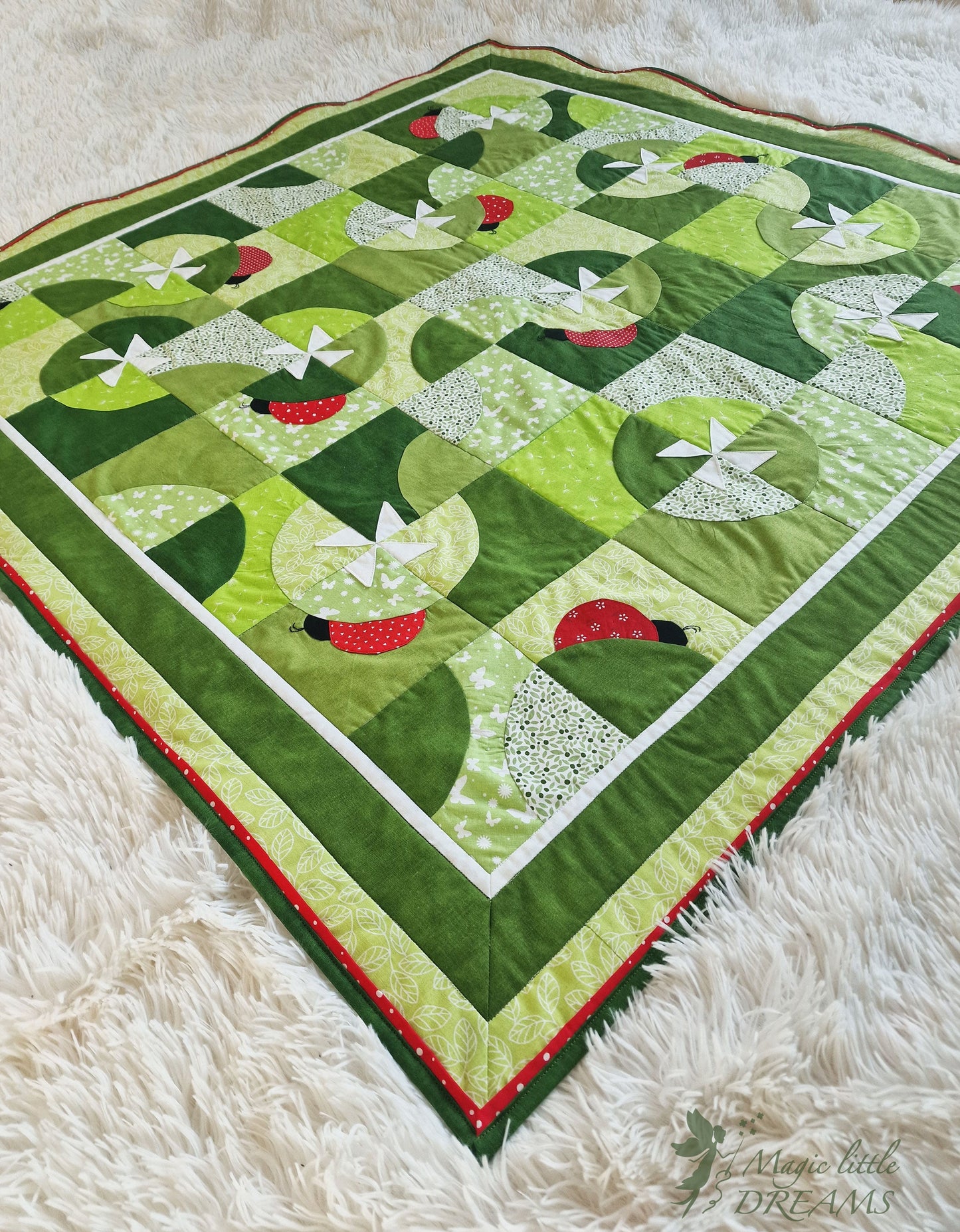 Diagonal view of the Ladybug Wonderland quilt, showing the full design with ladybugs, pinwheel flowers, and vibrant green and red colors.