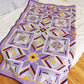 Diagonal display of 'More than Words' quilt, folded to reveal vibrant colors and geometric patterns.