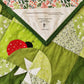 Close-up of the Ladybug Wonderland quilt, featuring a red ladybug, a pinwheel flower, and the quilt label, showcasing the playful design and the quilts personalized touch.