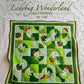 Cover of the Ladybug Wonderland baby quilt pattern, featuring a whimsical design with ladybugs, pinwheel flowers, and quarter-circle blocks in vibrant colors. Perfect for creating a charming quilt for a baby girl.