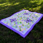 Purple butterfly quilt on green grass