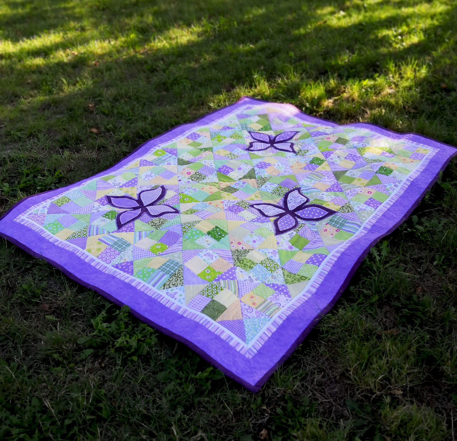 Purple butterfly quilt on green grass